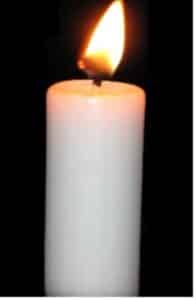 a white candle with a large yellow flame burning, against a black background with nothing else visible